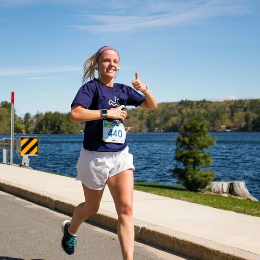 Runner giving a thumbs up mid-race on a lakeside road